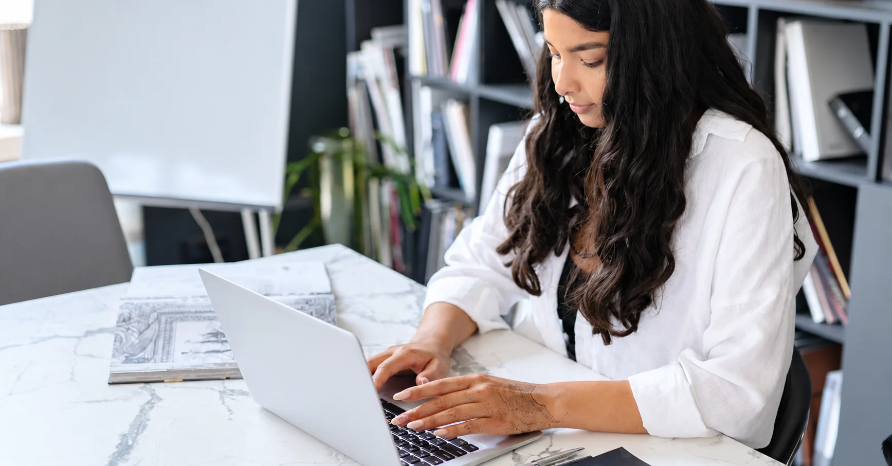 A person working at a laptop in a naturally lit office.