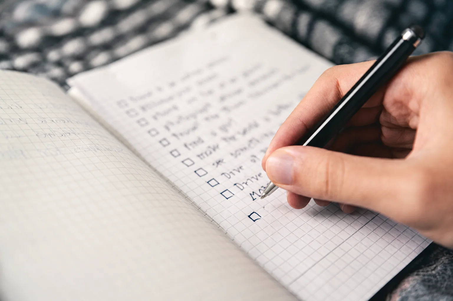 A real notebook and pen used to record a written checklist.